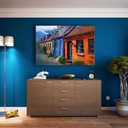 Eine blaue Wohnungswand. Davor angeordnet: Schränke, Pflanzen und eine Lampe.