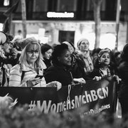 Schwarzweißfotos. Frauen auf einem Frauenmarsch in Barcelona halten ein Transparent hoch.