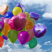 Viele bunte Ballons vor einem blauen Himmel mit weißen Schönwetterwolken.