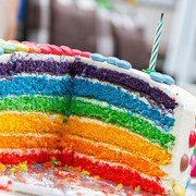 Eine aufgeschnittene Torte. Die einzelnen Tortenböden in verwschiedenen Regenbogenfarben.