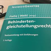 Ein Buch mit Gesetzestexten. Im Hinterrgrund ein Mikrophon.